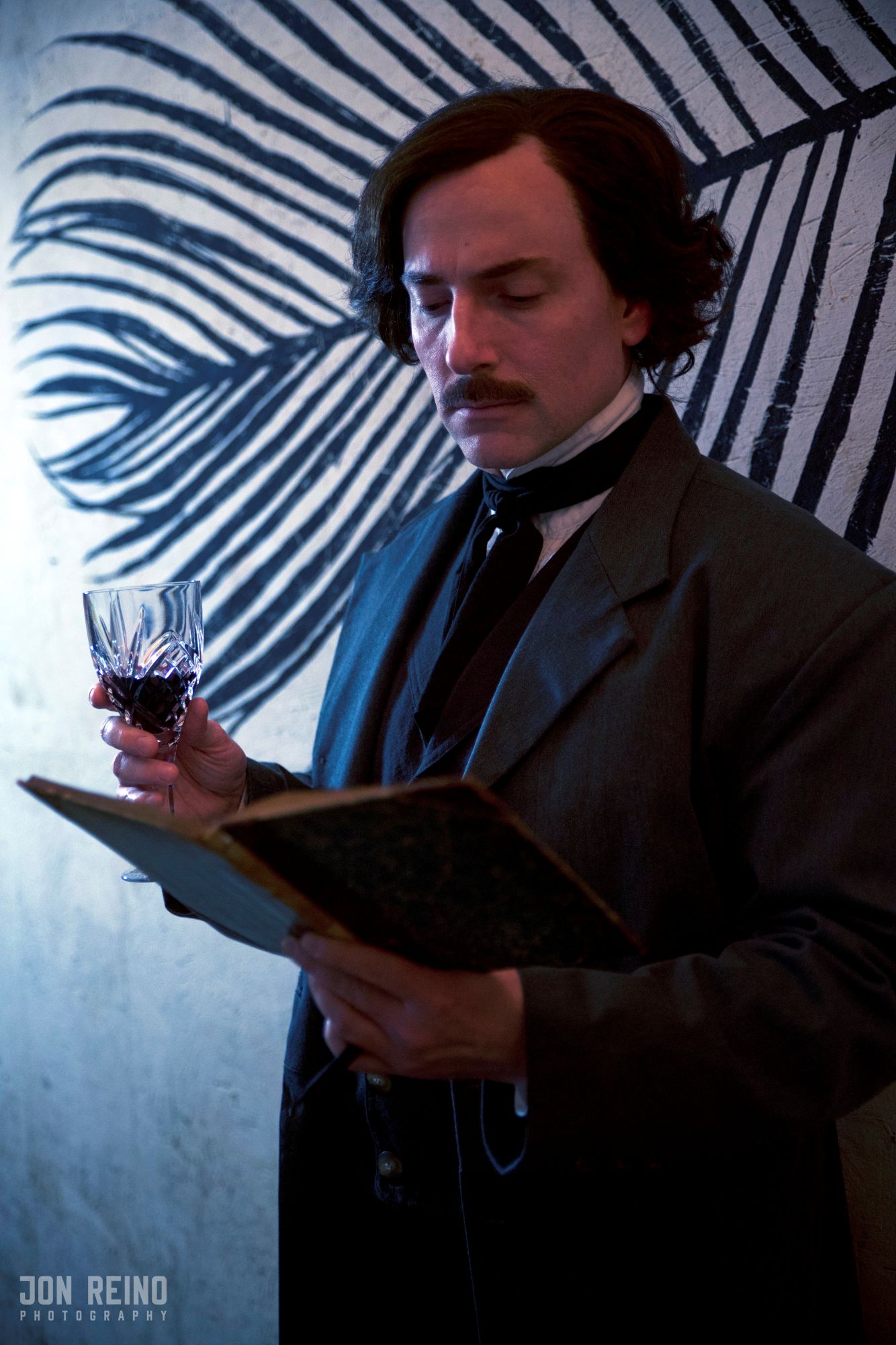 Campbell Harmon as Edgar Allan Poe in front of a feather mural.