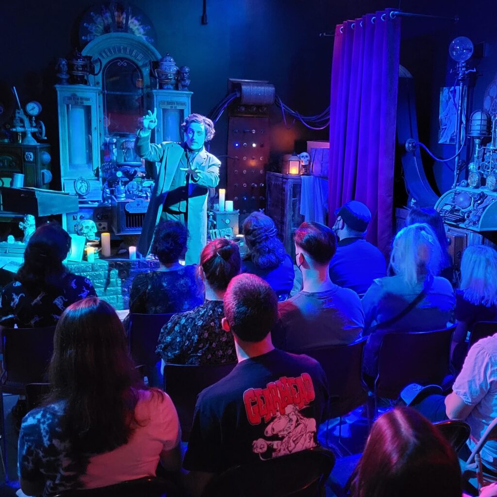 Campbell Harmon as Edgar Allan Poe performing with an audience in a dramatically lit theater